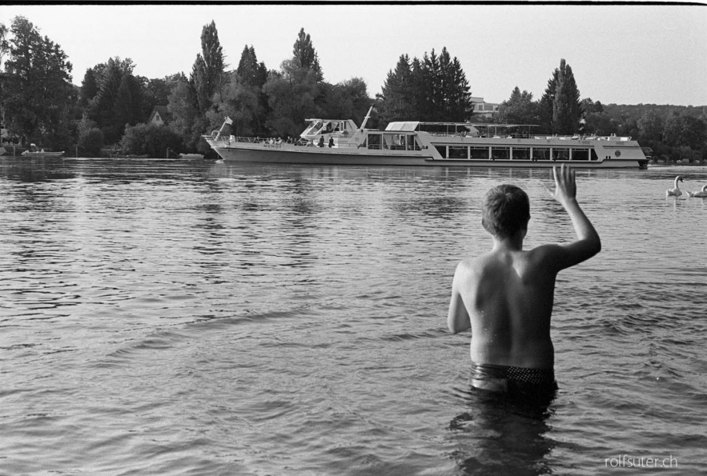 Swimmer waving at a boat